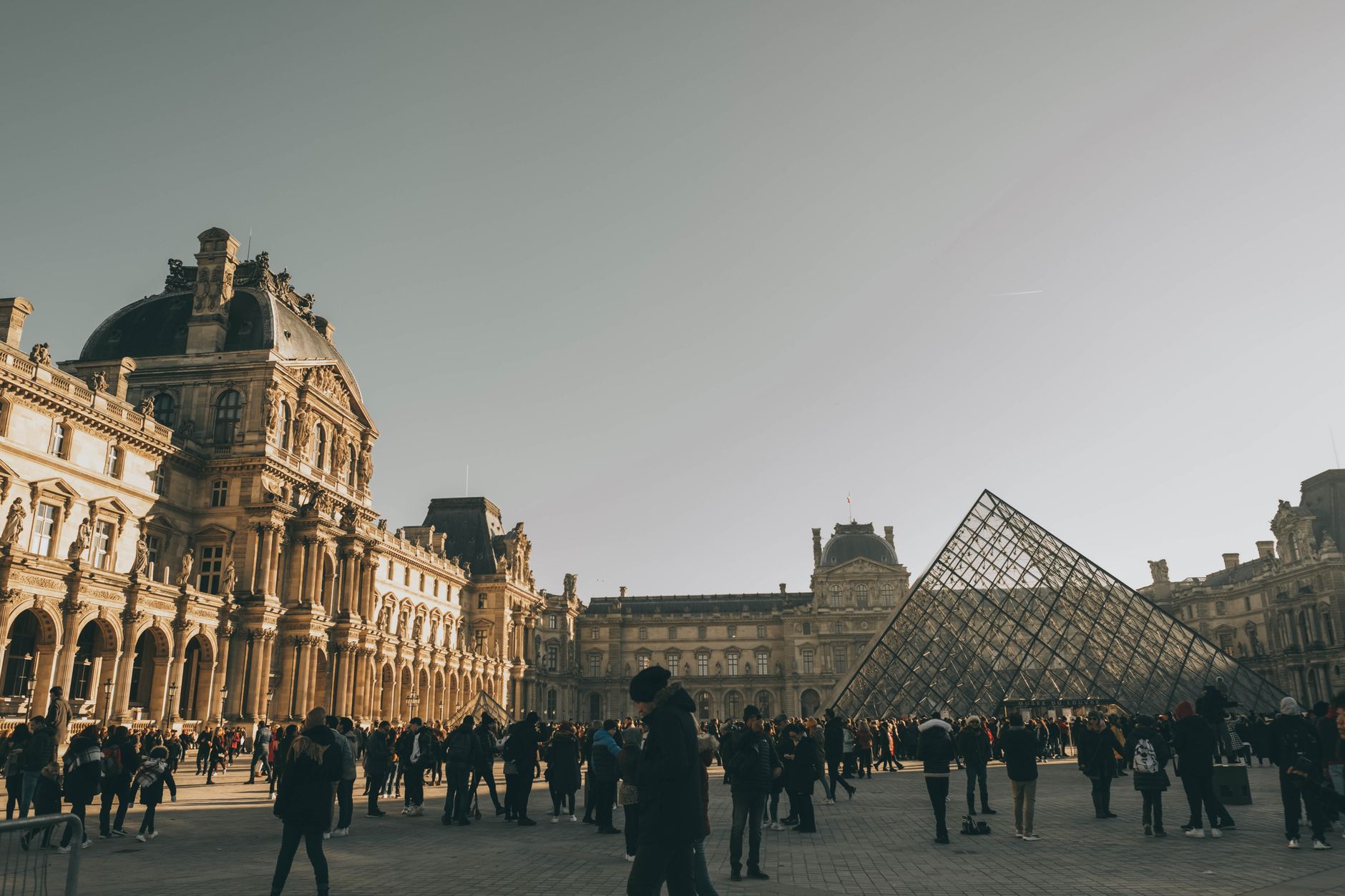 Tourists at the Louvre Museum with the iconic glass pyramid in Paris, France. — Discover the Best Pesach Programs for 2024: T