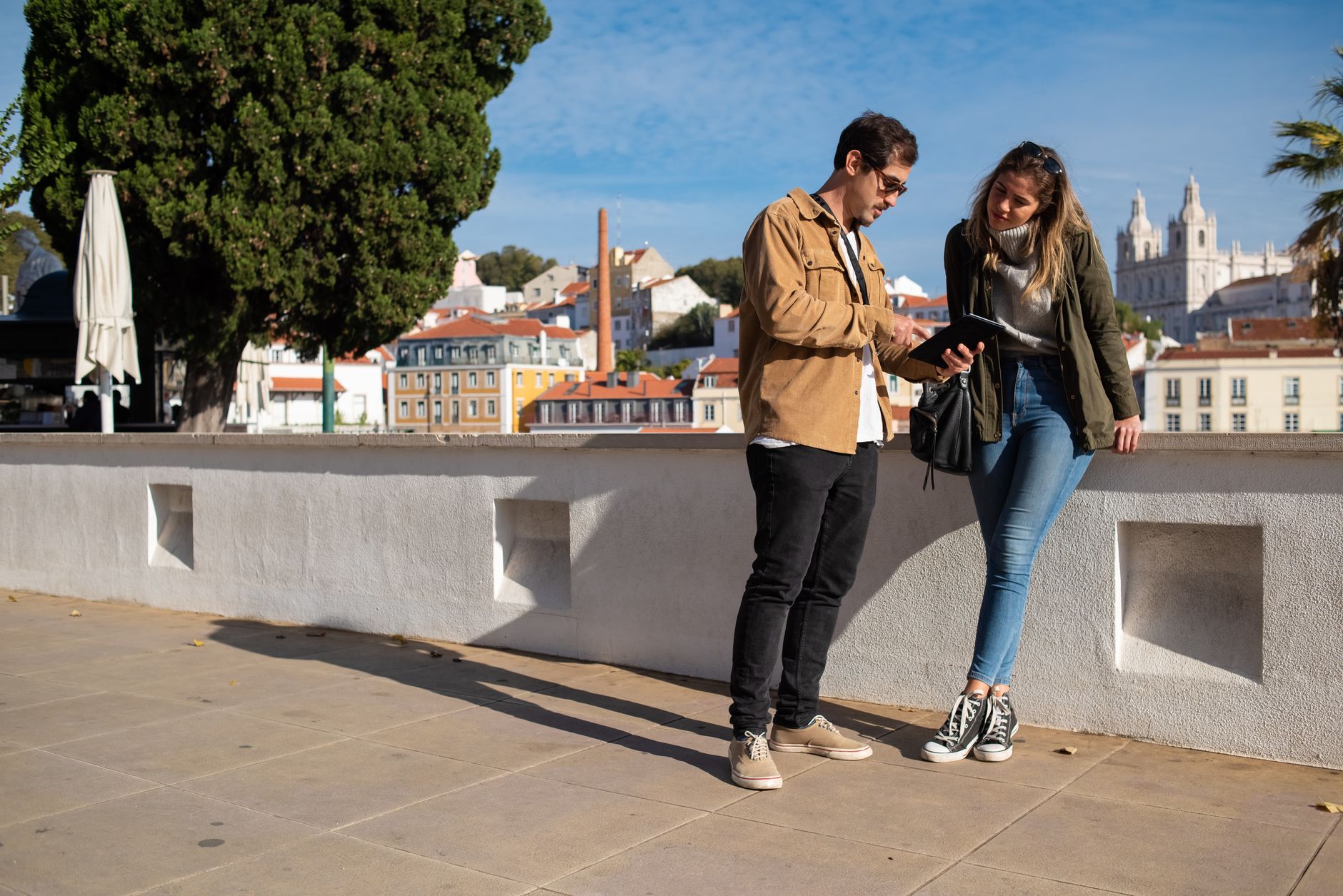 A couple using a tablet in an urban setting with a scenic backdrop, perfect for travel themes. — How to Play and Win in the T
