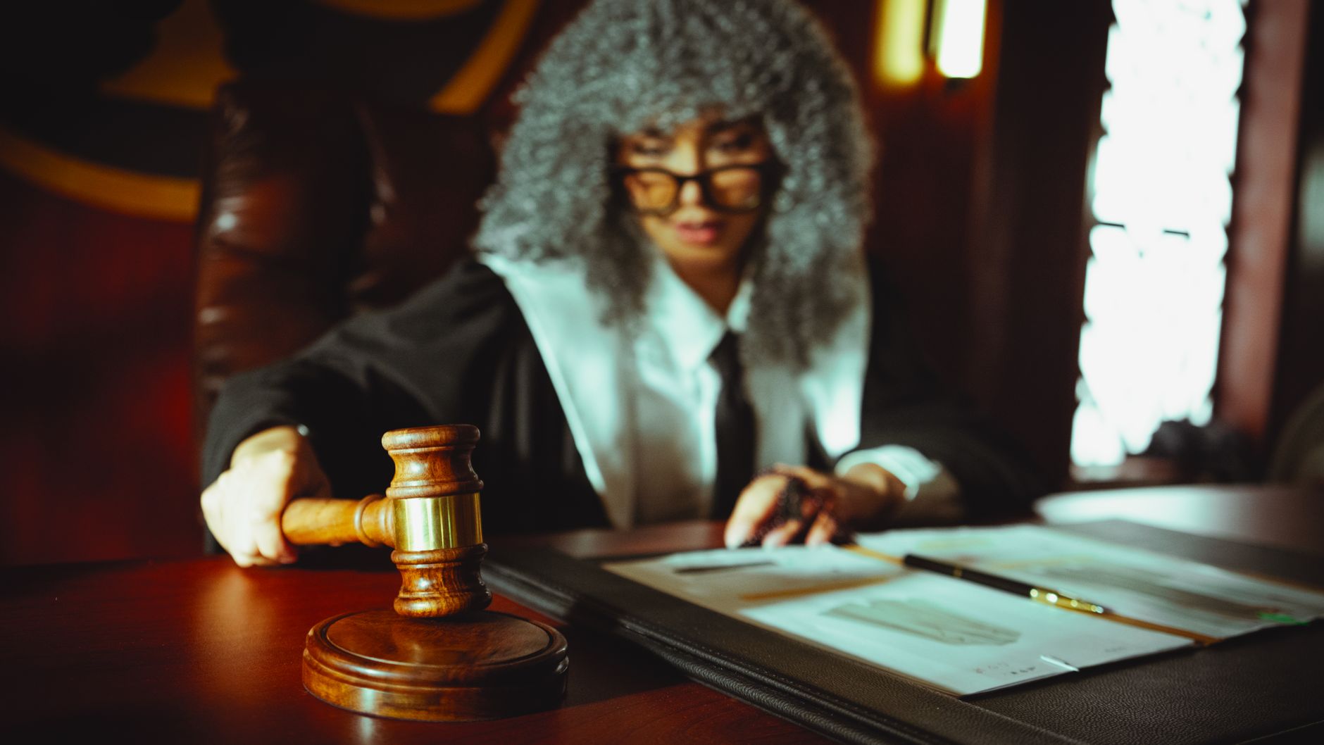 Female judge in a courtroom setting, focusing on legal documents with a gavel. — Patent lawyer services in Colorado supportin