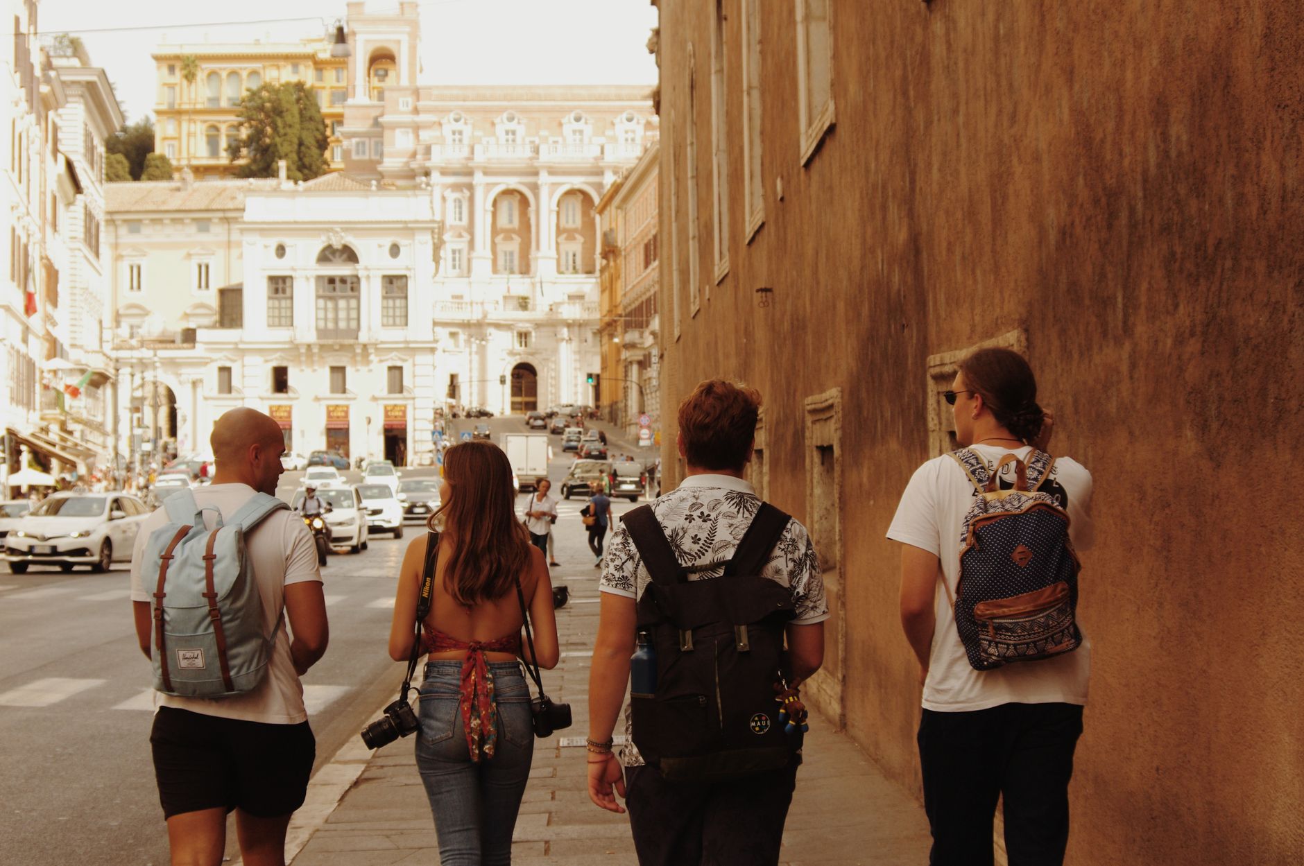 Four tourists with backpacks walking on a street in Rome, Italy, with historic architecture around. — Teen Patti Strategy Tha