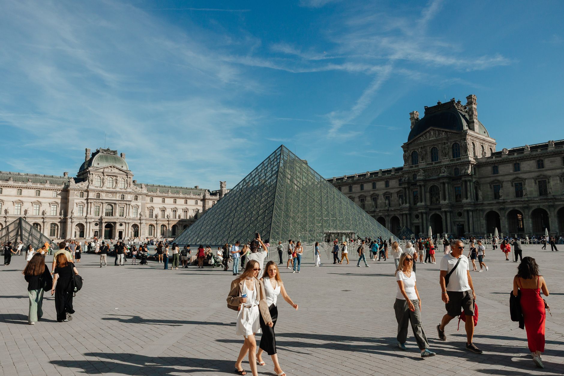Crowds gather around the iconic glass Pyramid of the Louvre Museum in Paris, France on a sunny day. — Why BDG Game Is the New