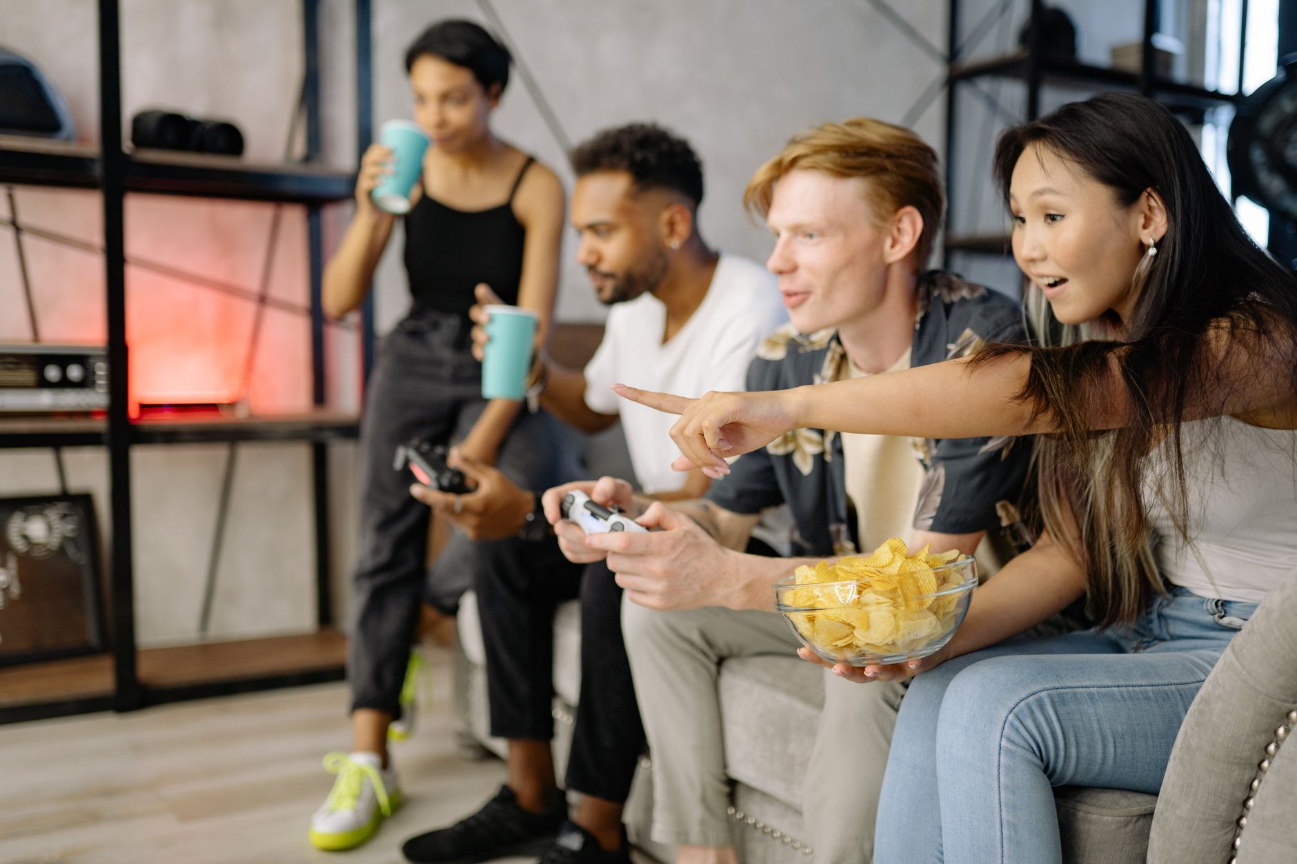 Diverse group of friends enjoying video games and snacks in a cozy living room setting. — Why does minesweeper appeal to puzz
